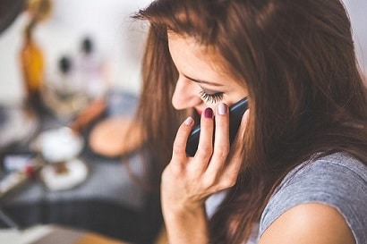 Une femme parlant au téléphone portable devant un miroir.